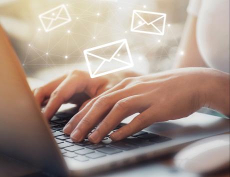 Mains rédigeant un e-mail de candidature sur un ordinateur portable