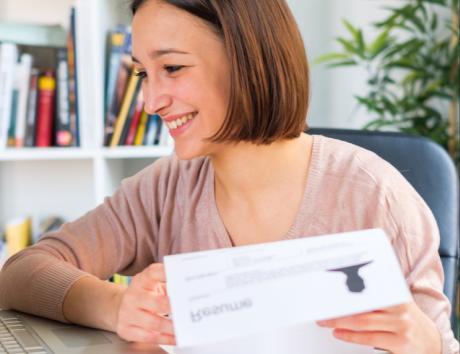 Femme souriante tenant un CV, illustrant l’utilisation d’un titre de CV clair et professionnel