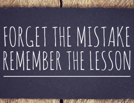 Panneau sur fond en bois avec la citation 'Forget the mistake, remember the lesson', illustrant un article sur les erreurs courantes à éviter dans un CV