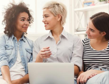 Trois femmes échangeant devant un ordinateur portable, illustrant la rédaction d’une phrase d’accroche pour un CV